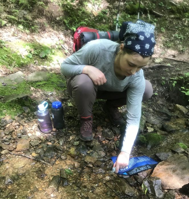 A writer placing the Sawyer bag in a small stream