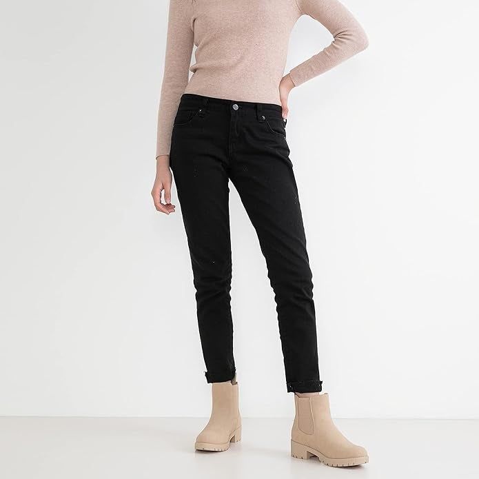 A person models black jeans and beige ankle boots, wearing a fitted long-sleeve top, with their head cropped out of the shot