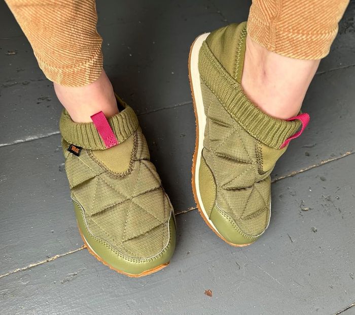 A reviewer is seen wearing the green quilted slip-on shoes, showcasing their stylish and comfortable design