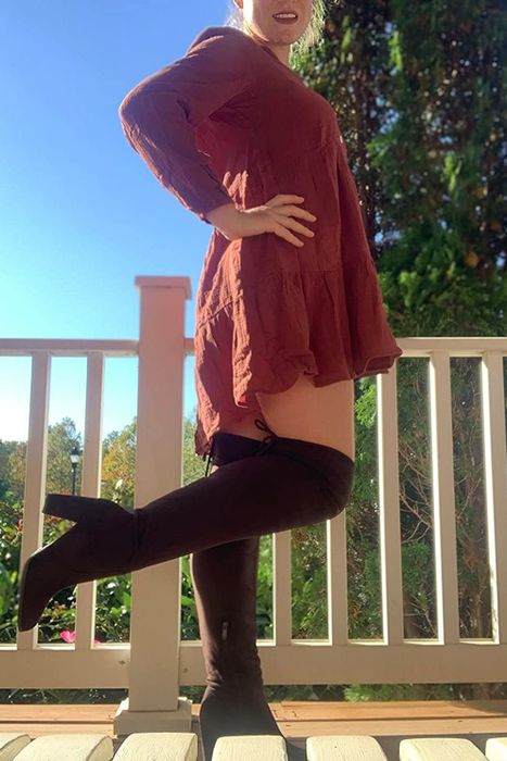 A reviewer styling brown boots with a red dress