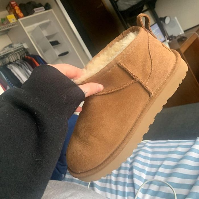 A reviewer holding the brown short Ugg boots