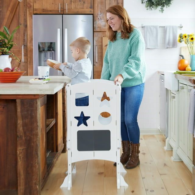 The tower with a toddler standing inside at a kitchen counter, with a model of the setup visible in the background.