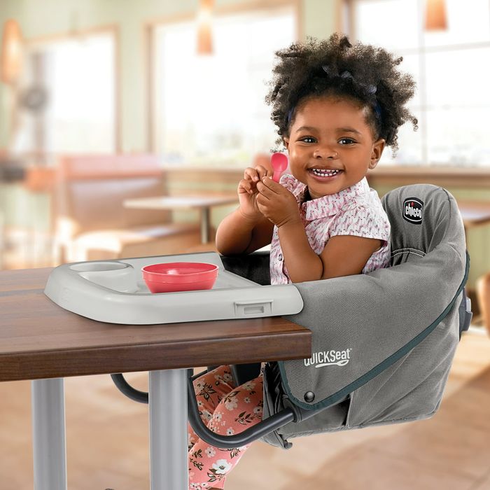 A baby sitting in a chair attached to a table.
