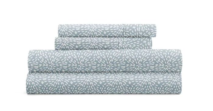 A stack of folded bed sheets with a delicate white floral design on a soft backdrop, perfect for home decor or bedding shopping articles.