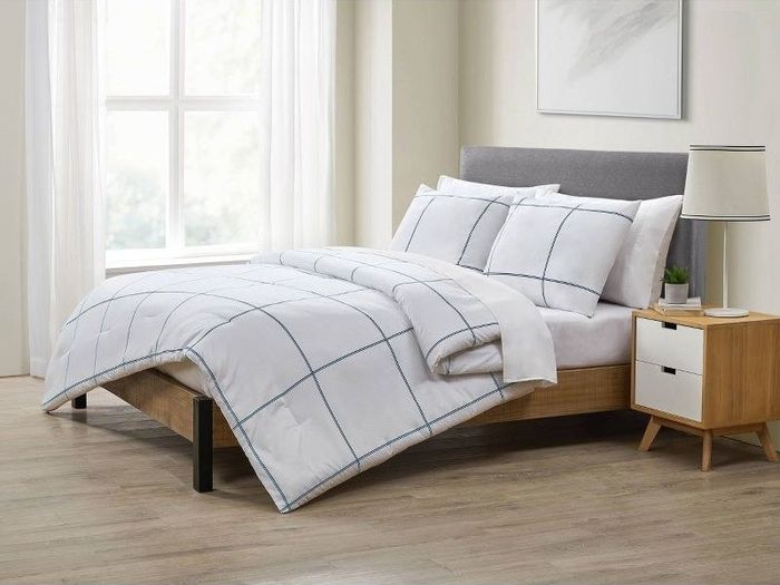 A white comforter paired with matching sham pillows showcasing a large blue plaid pattern.