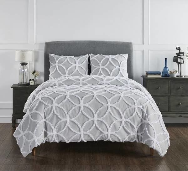The comforter is a cozy blend of gray and white with a tufted design.