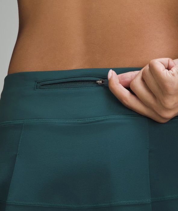 a close-up showing the zippered back pocket of a teal skirt