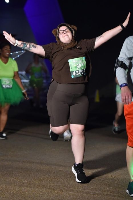 A reviewer with arms extended, standing at a nighttime race, dressed in black shorts.
