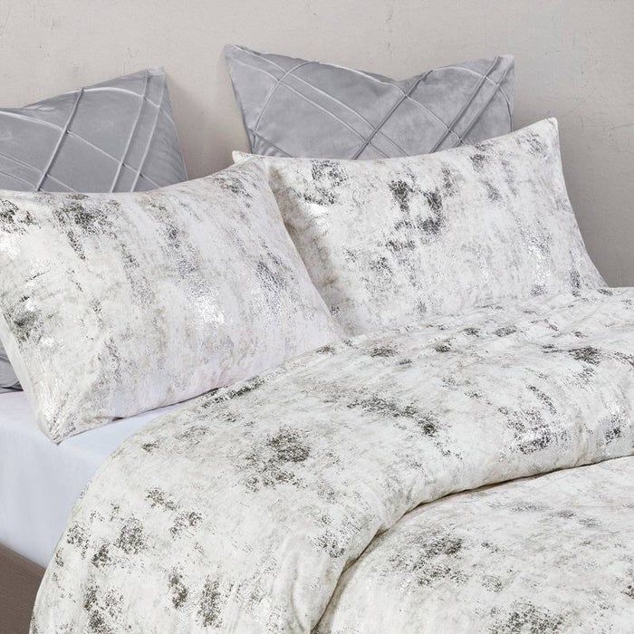 A white comforter with silver metallic accents and matching sham pillows