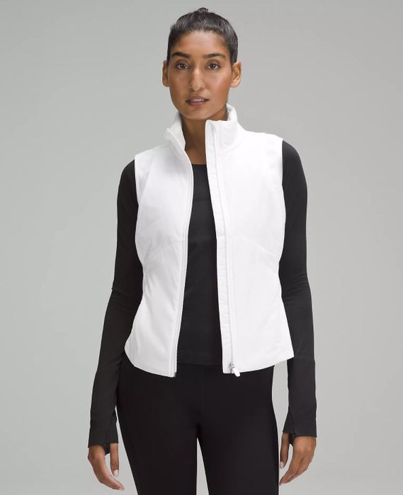 A different model is seen sporting a white vest layered over a black long-sleeve shirt.