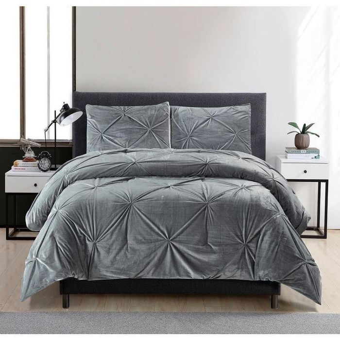A gray velvet comforter with matching sham pillows, featuring a hand-tufted design.