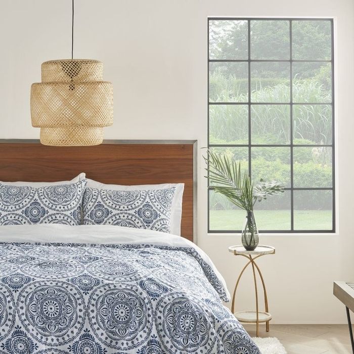 A white comforter and sham pillows featuring a detailed blue pattern.