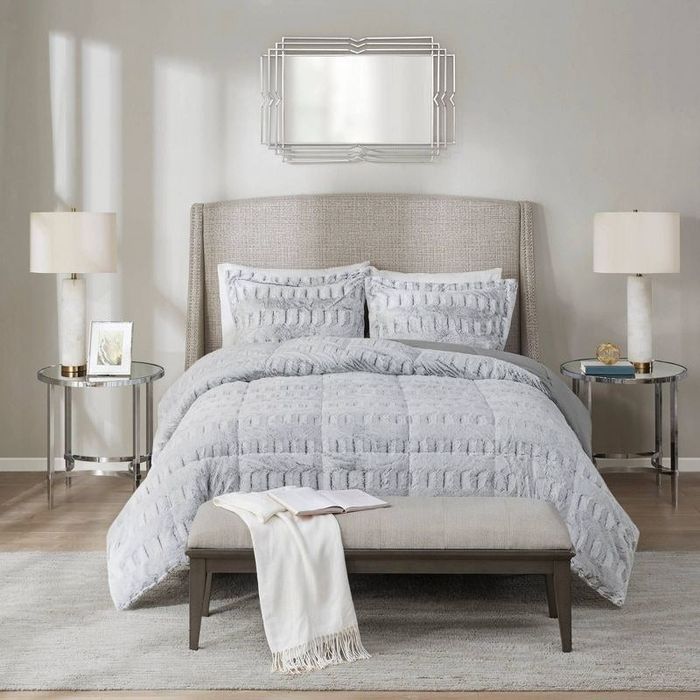 A gray faux-fur comforter and matching sham pillows.
