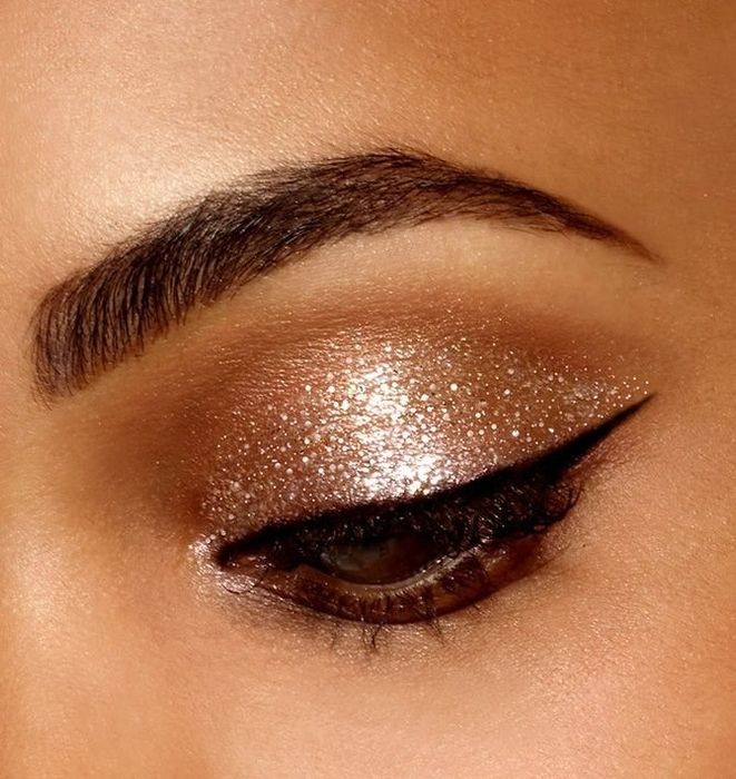An eye adorned with sparkling gold eyeshadow and a sharp cat-eye liner