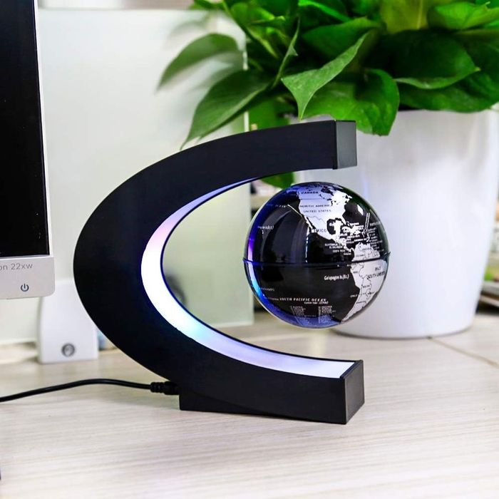 A globe floating effortlessly within a C-shaped light stand.