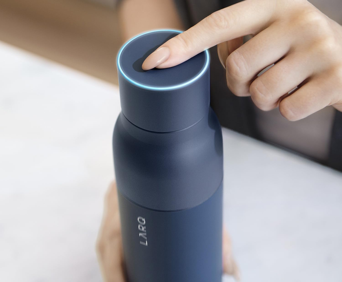 A person using a UV-C light water bottle, pressing a button to purify the water in just 60 seconds