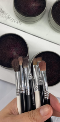 image of a makeup brush cleaning tin alongside various brushes