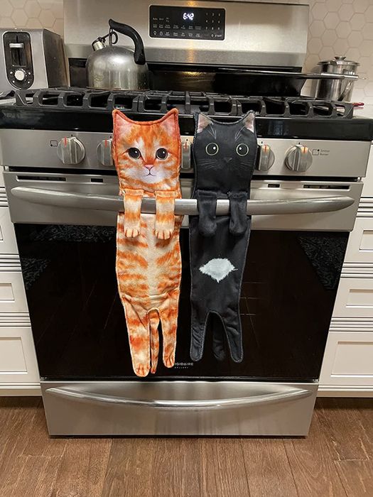 an orange cat towel and a black cat towel hanging from a reviewer’s oven door