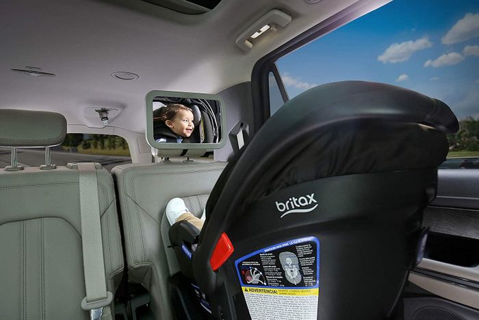 a mirror mounted on a headrest with a baby gazing into it