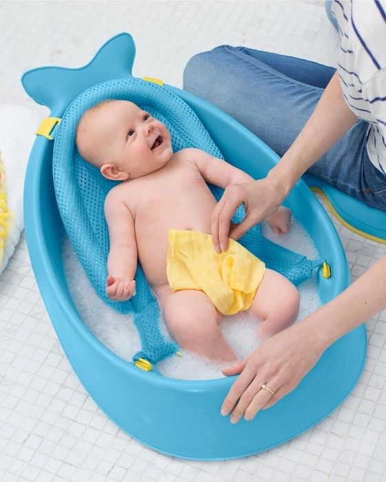 A baby enjoying a bath in a charming whale-shaped tub.