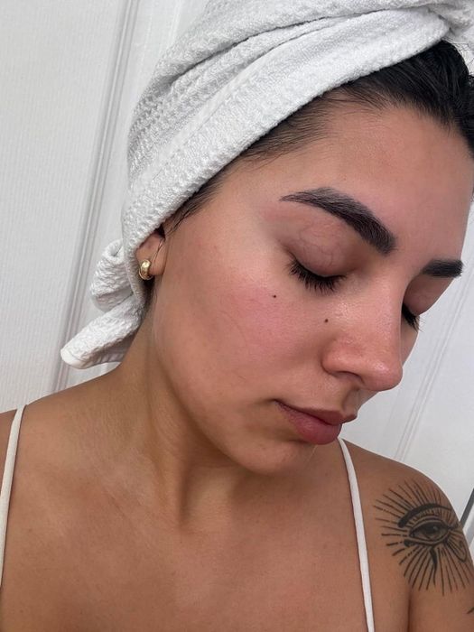 A person with closed eyes and flawless skin, their hair wrapped in a towel