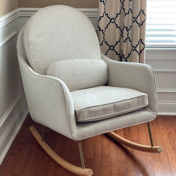 A gray rocking chair with a round back, praised by a reviewer for its comfort and style, especially for those long hours spent rocking your baby.