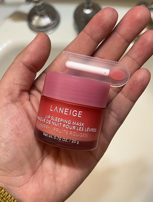 A reviewer holding the lip mask jar along with its applicator