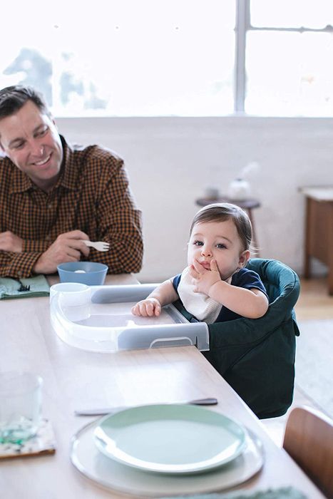 A baby enjoying their meal while seated in the high chair
