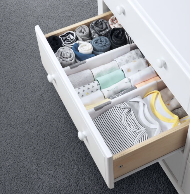 A drawer organized with dividers, neatly separating baby clothes for easy access.