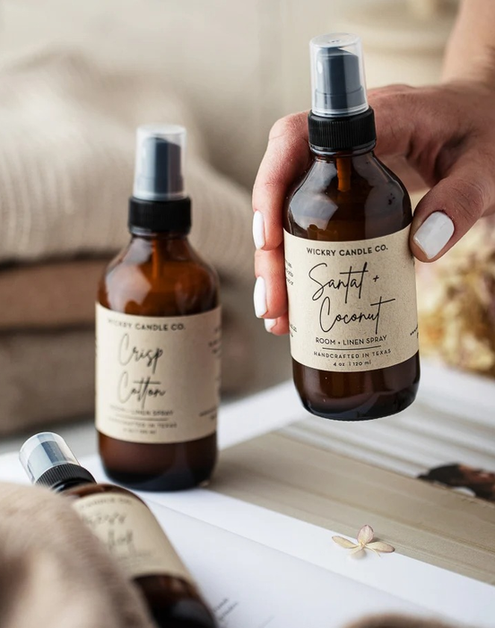 a model holding a bottle of room spray alongside two other bottles in various scents