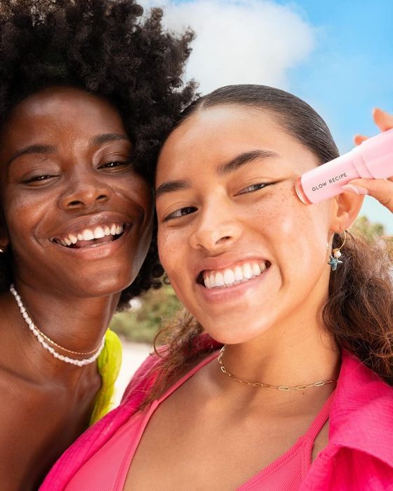 Two models smiling; one holds a Glow Recipe product near her face