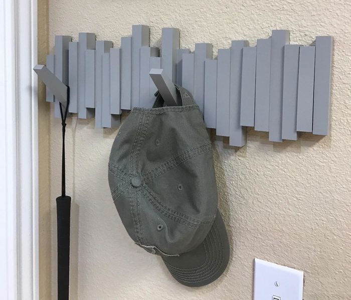a reviewer's image of the gray wall-mounted hooks holding a hat and an umbrella