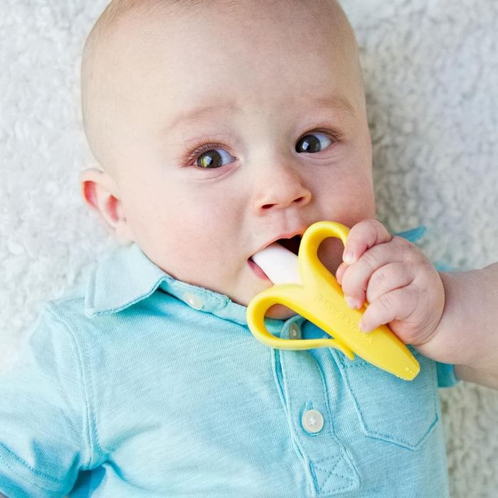 a baby gnawing on a banana-shaped teether