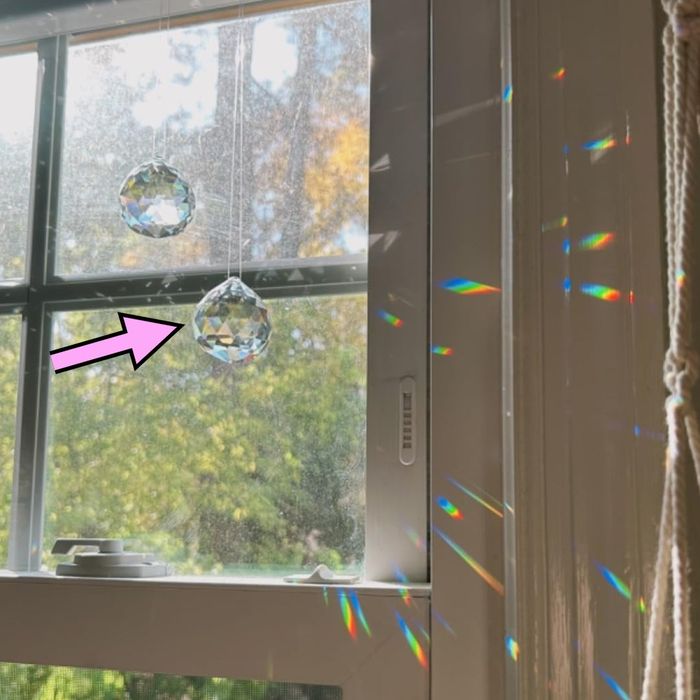 Crystal suncatchers hanging on a window, projecting rainbow patterns onto a wall