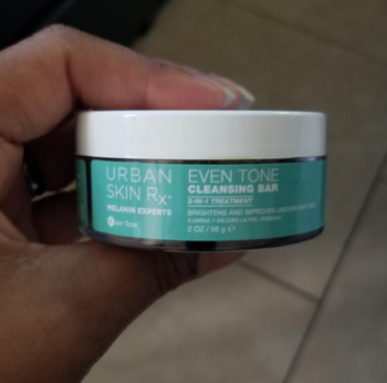 A reviewer holding the jar of the cleansing bar.