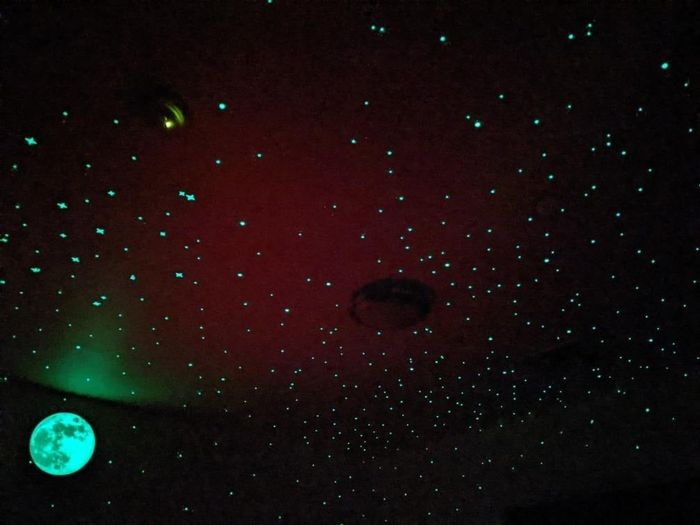 A ceiling adorned with glowing stars and a moon decal, creating a serene starry night effect ideal for a calming room atmosphere
