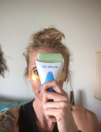 A reviewer holding a green facial ice roller to their face.