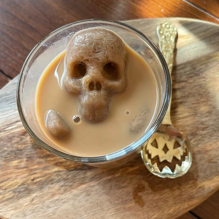 A skull-shaped ice cube floating in a cup of coffee