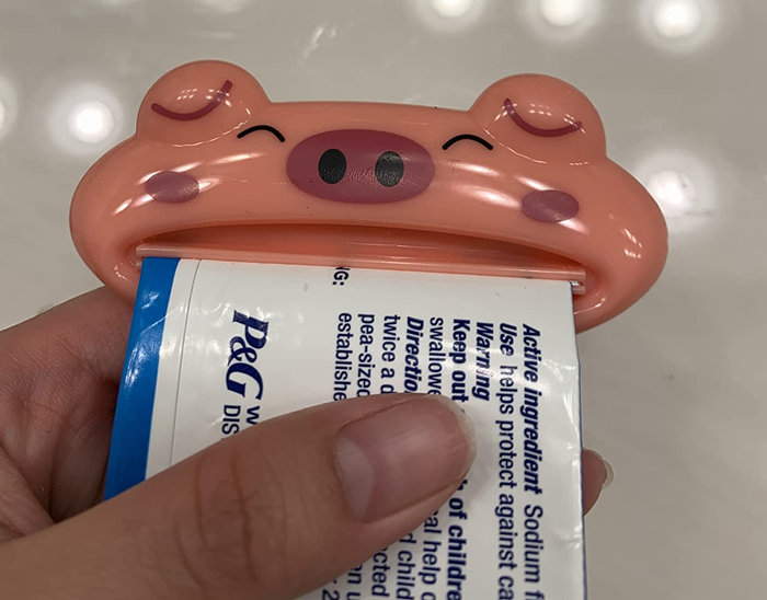A reviewer demonstrating the tube squeezer on a toothpaste tube
