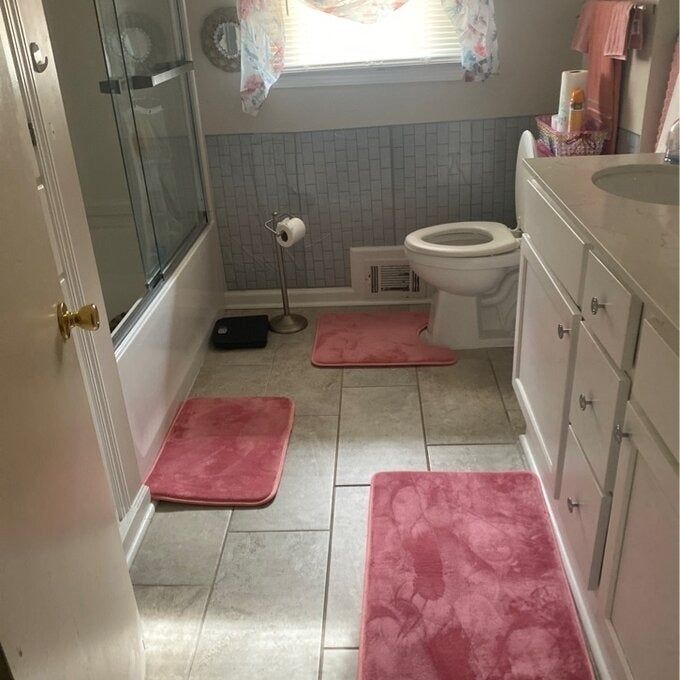 Three pink bath mats neatly placed in a bathroom