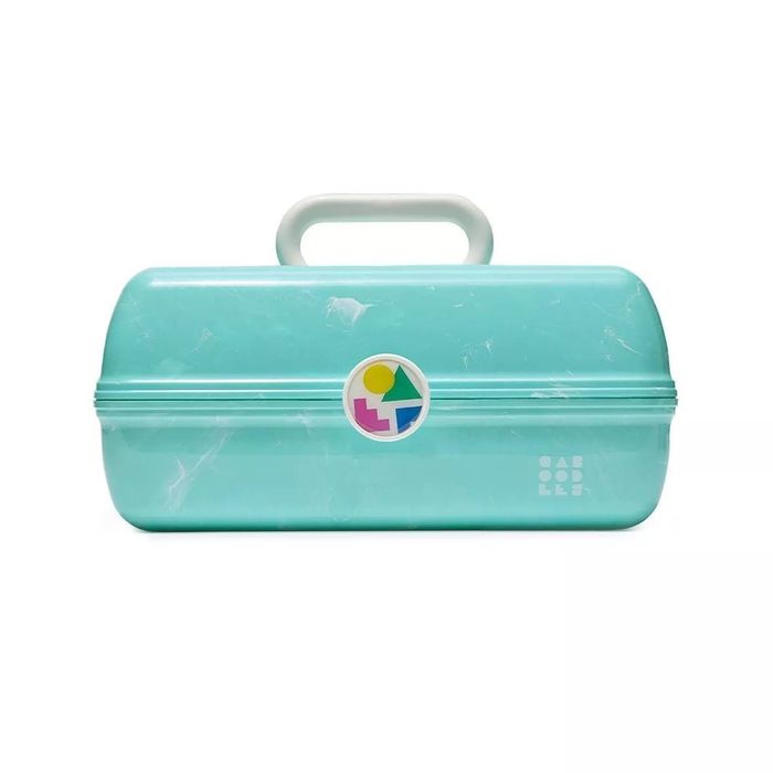 A vintage-style teal Caboodles case featuring a handle and a white retro logo on the front, highlighted in a shopping article as a must-have accessory