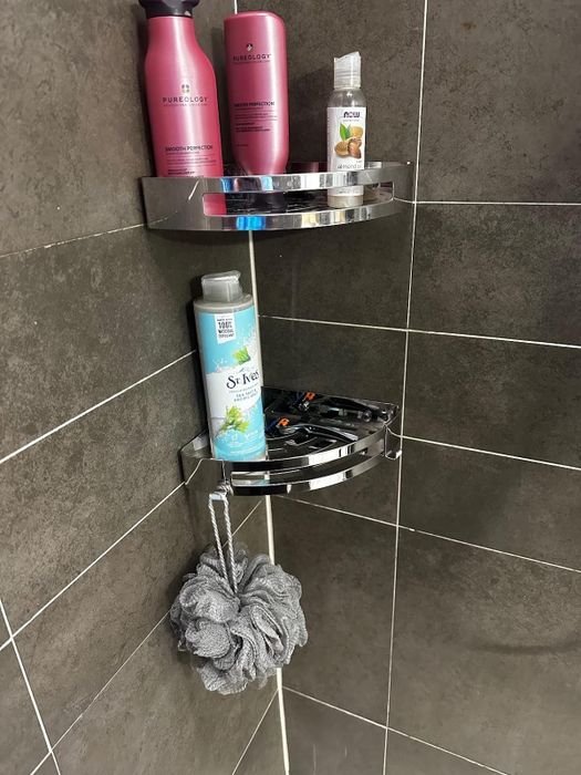 Another reviewer's photo of chrome shelves in a marble shower, neatly holding various bottles