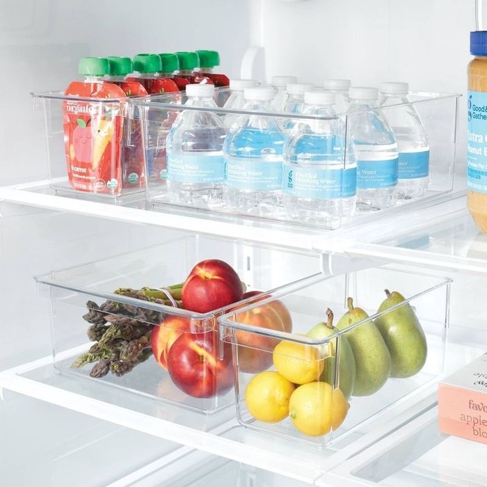 Refrigerator with clear storage bins filled with applesauce pouches, water bottles, asparagus, peaches, pears, and lemons. All neatly organized for easy access.