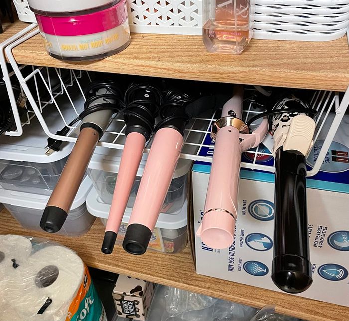 The same reviewer demonstrates another under-shelf basket being used to store styling tools, showcasing its versatility.