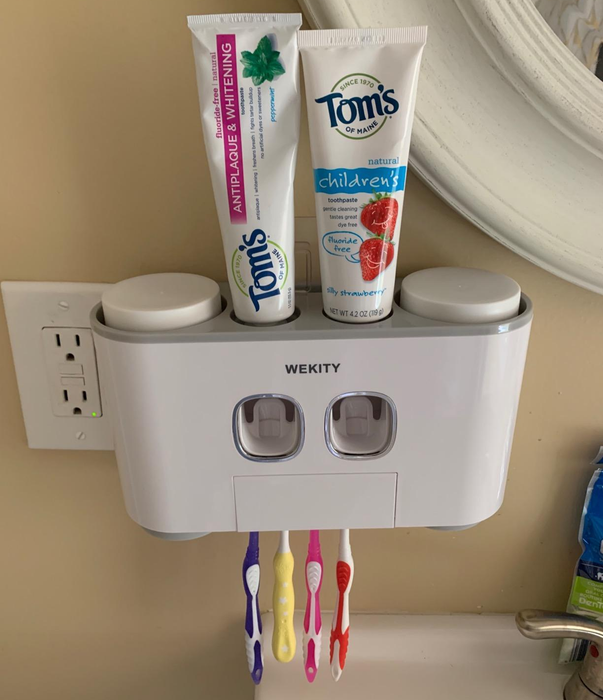 A reviewer’s white holder is mounted on the bathroom wall, neatly storing toothpaste bottles and toothbrushes.