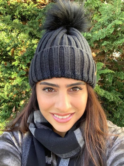 A reviewer wearing a black knitted beanie adorned with a black pom-pom.
