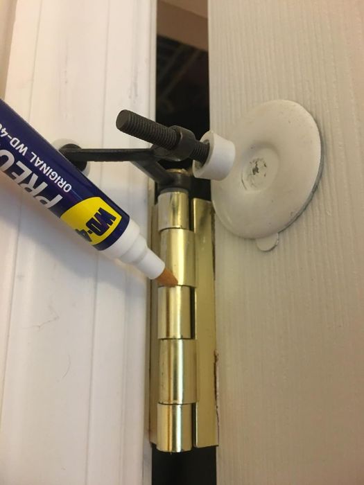 A reviewer applying the WD-40 pen to a door hinge.