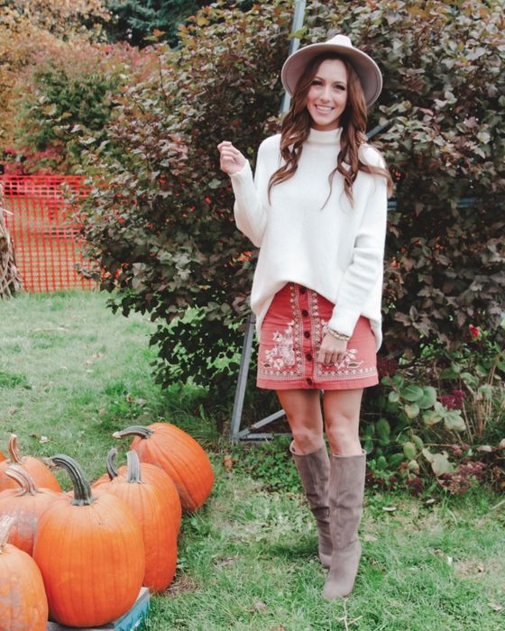 A reviewer showcasing an oversized cream-colored sweater.