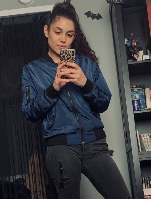 A reviewer wearing a blue bomber jacket with a black zipper.