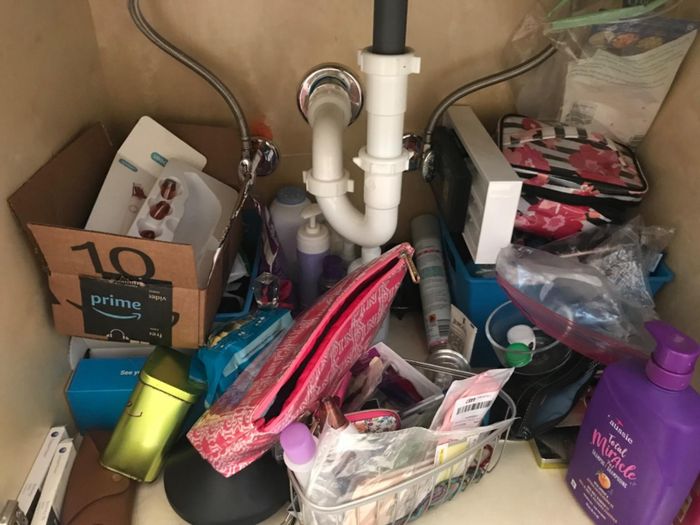 A reviewer's under-sink cabinet cluttered with various items.
